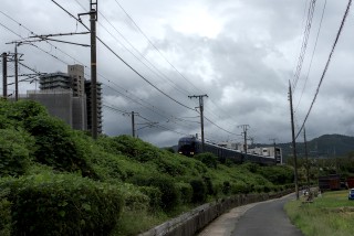 A train entering Torokko Kameoka Station on a cloudy, windy day.